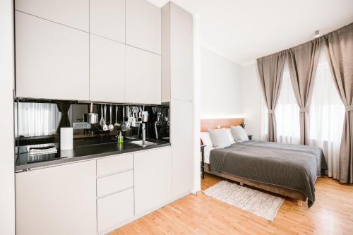 a white bedroom with a bed and a kitchen at Karlo Main Square Apartments in Zagreb