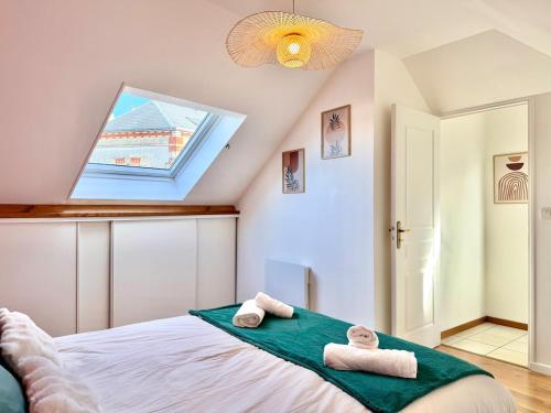 a bedroom with two towels on a bed with a window at Maison Bellebat - proche d'Orleans in Orléans
