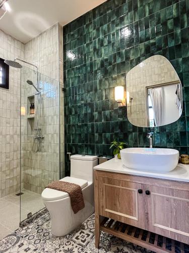 a bathroom with a sink and a toilet and a mirror at Cococreek Kohkood in Ban Khlong Mat