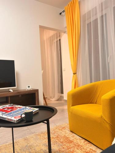 a living room with a yellow chair and a table at Yellow Dawn Modern Flat in Quiet Area with Garage Parking and Self Check-In in Rediu