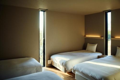 two beds in a small room with windows at Hiire IZU OLIVE in Ito