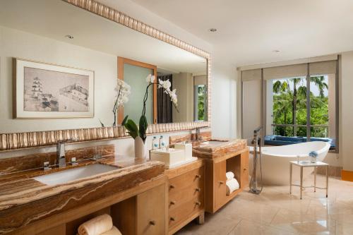 a bathroom with a tub and a large mirror at The Mulia in Nusa Dua