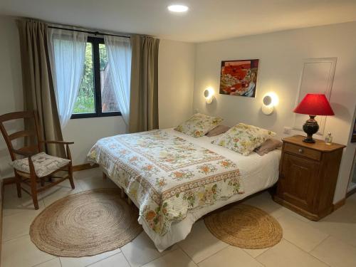 a bedroom with a bed and a chair and a window at Les chambres de La Serre in Camarès
