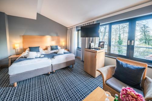 a bedroom with a bed and a tv and a couch at Hotel Esplanade Resort & Spa - Adults Only in Bad Saarow