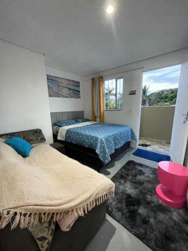 a bedroom with two beds and a window at Pousada Ideal Guarujá - Estúdios Família & Quartos in Guarujá