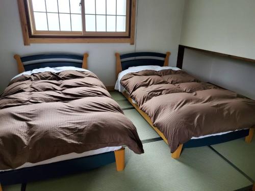 two beds sitting next to each other in a bedroom at Hakuba Inn Bloom - Vacation STAY 95727 in Hakuba