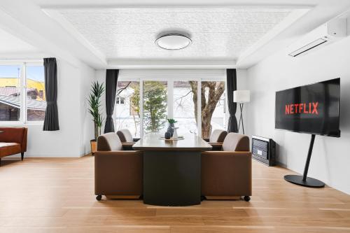 a living room with a table and chairs and a tv at Nord Birch in Tōbetsu