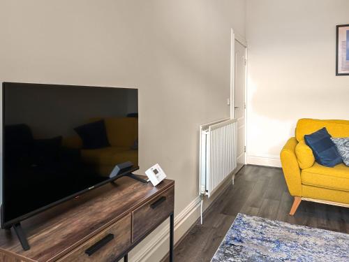 ein Wohnzimmer mit einem großen Fernseher und einem gelben Sofa in der Unterkunft Dingleton 45 in Melrose