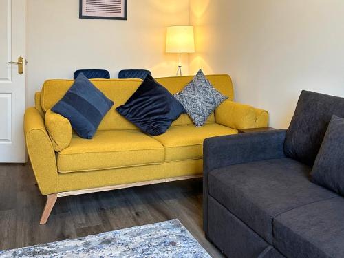 ein gelbes Sofa mit Kissen darauf in einem Wohnzimmer in der Unterkunft Dingleton 45 in Melrose