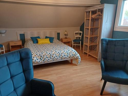 a bedroom with a bed with a yellow pillow and two chairs at Les Puits Bessin Normandie in Sommervieu