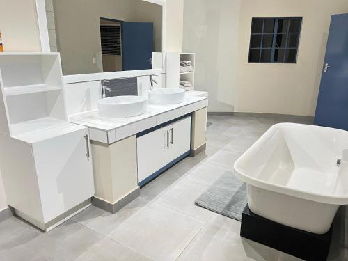 a white bathroom with two sinks and a tub at Valley Croft Farm in Hekpoort