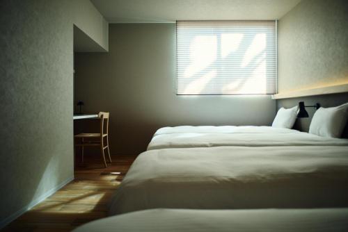 a bedroom with two beds and a desk and a window at Hiire IZU OMURO in Ito