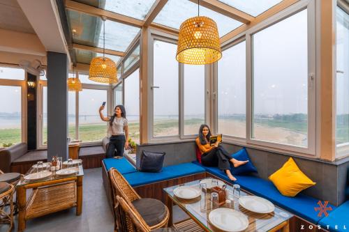 two women standing in a restaurant with windows at Zostel Guwahati in Guwahati