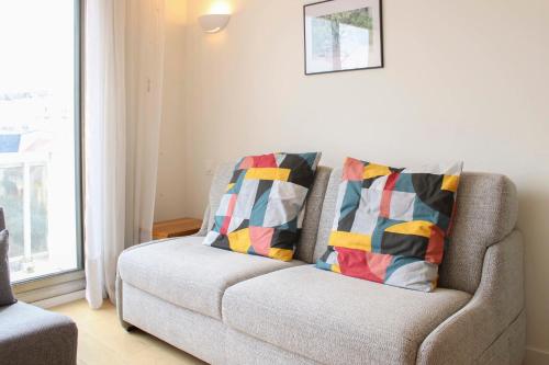 a living room with a couch with two pillows at Renovated studio with quiet balcony in Bois-Colombes
