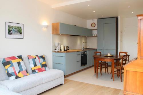 a kitchen and living room with a couch and a table at Renovated studio with quiet balcony in Bois-Colombes