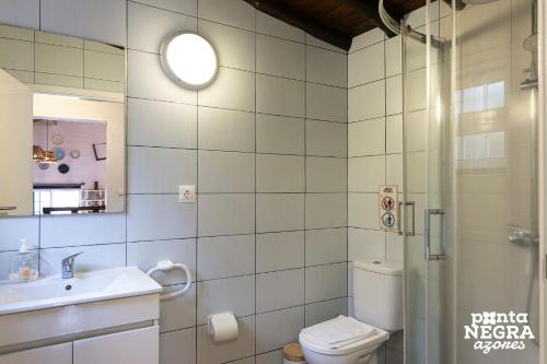 a bathroom with a toilet and a sink and a shower at Alojamento Ponta Negra in Biscoitos