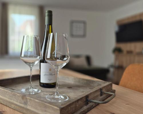 two wine glasses on a tray with a bottle of wine at Landhotel Kachelofa in Vaihingen an der Enz