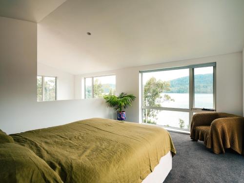 a bedroom with a large bed and a large window at Tasman Tides - Architecturally-designed holiday home in Eaglehawk Neck