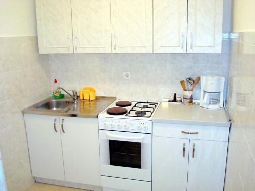 a white kitchen with a stove and a sink at Apartment Medulin 10 in Medulin