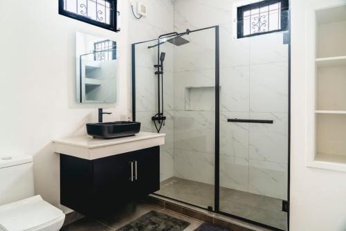 a bathroom with a glass shower and a sink at Mango House - 2 Bedrooms & Private Pool in La Gaulette