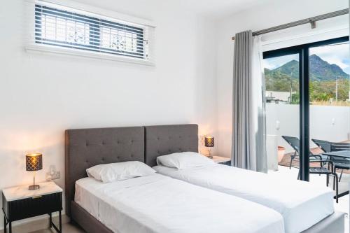 two beds in a bedroom with a view of a balcony at Mango House - 2 Bedrooms & Private Pool in La Gaulette