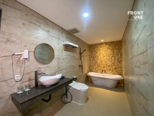 a bathroom with a sink and a tub and a toilet at Front One The Andia Boyolali in Boyolali