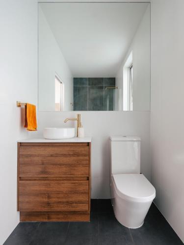 a white bathroom with a sink and a toilet at Tasman Tides - Architecturally-designed holiday home in Eaglehawk Neck