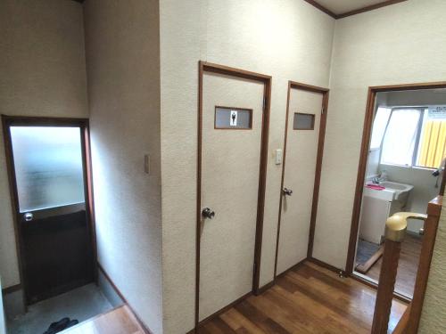 an empty room with two doors and a sink at OZigaoka Guest House in Otsu