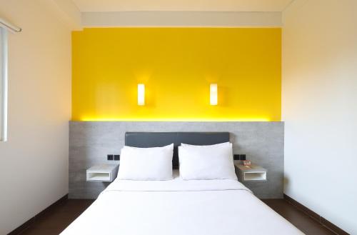 a bedroom with a white bed and a yellow wall at Amaris Hotel Bekasi Barat in Bekasi