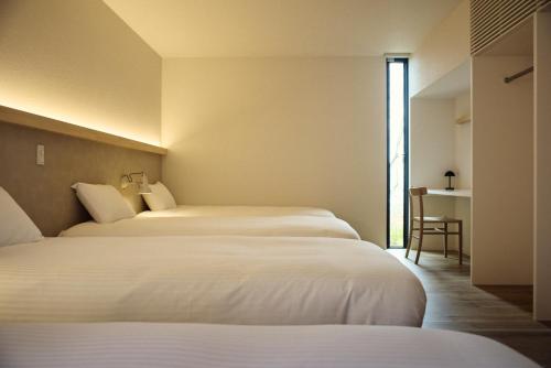a hotel room with two beds and a window at Hiire IZU FUTO in Ito