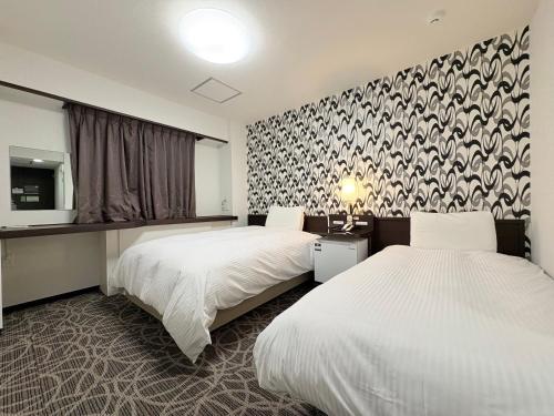 a hotel room with two beds and a wall at APA Hotel Okhotsk Kitami in Kitami