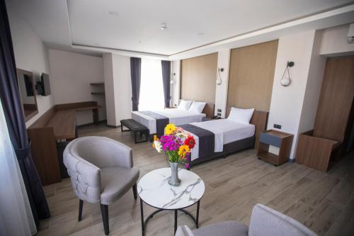 ein Hotelzimmer mit zwei Betten und einem Tisch mit Blumen in der Unterkunft Evdirhan Otel in Dosemealti