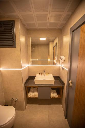 ein Badezimmer mit Waschbecken, Toilette und Spiegel in der Unterkunft Evdirhan Otel in Dosemealti