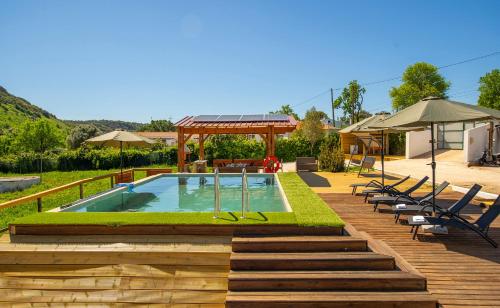 a pool with a deck and chairs and an umbrella at Quinta Silvestre in Bensafrim