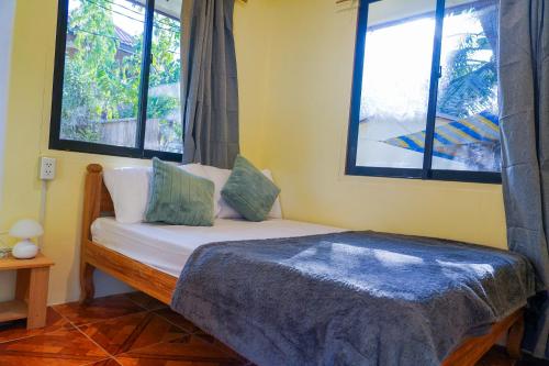 a bed in a room with two windows at Aman House in San Vicente