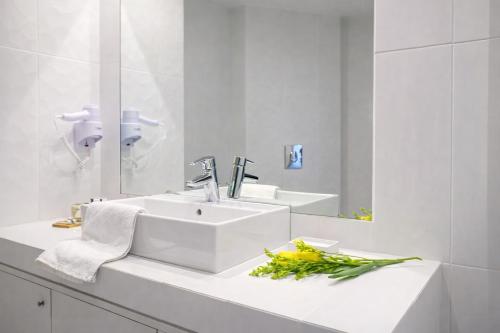 a white bathroom with a sink and a mirror at Lotus Center Inn in Athens