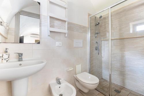 a bathroom with a sink and a toilet and a shower at Trulli degli Augelli by BarbarHouse in San Michele Salentino