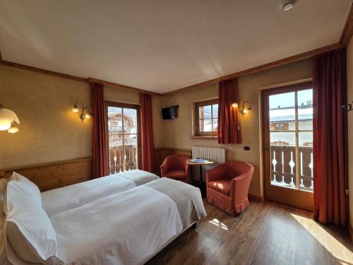 a bedroom with a large white bed and a chair at Hotel La Pastorella in Livigno