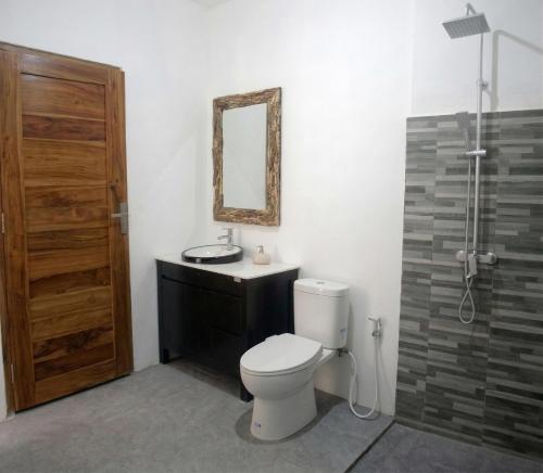 a bathroom with a toilet and a sink and a mirror at Winners surfing bali resort in Airsatang