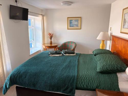 a bedroom with a green bed with a green blanket at Shipwright Inn in Pembroke Dock