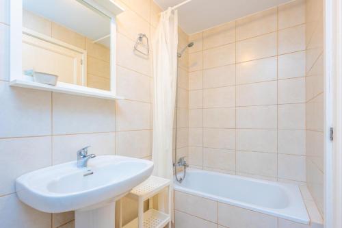 a white bathroom with a sink and a bath tub at Hotel Antares in Cala d´Or