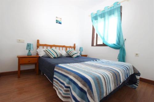 a bedroom with a bed with a blue blanket and a window at Mirador del Mediterraneo in Villamartin