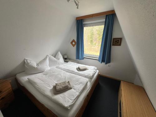 a bedroom with a bed with white sheets and a window at Ostseeferienhaus Finni in Ribnitz-Damgarten