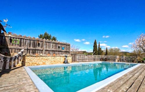 a swimming pool next to a wooden fence at Authentique Maison Piscine in La Cassaigne