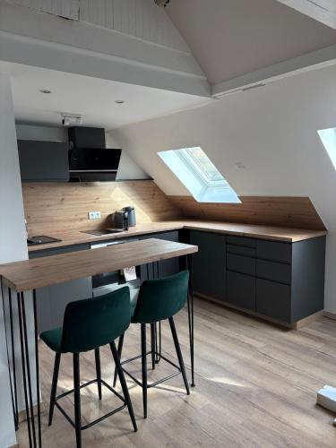 a kitchen with a wooden table and two green chairs at Au Petit Stub, studio 2 étoiles in Rosheim