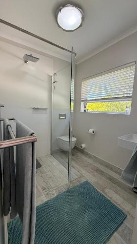 a bathroom with a shower and a toilet and a window at Hack's Shack in Cape Town
