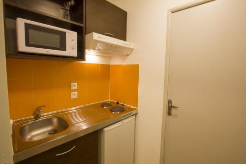 a kitchen with a sink and a microwave at ApartHotel Sainte-Marthe in Avignon