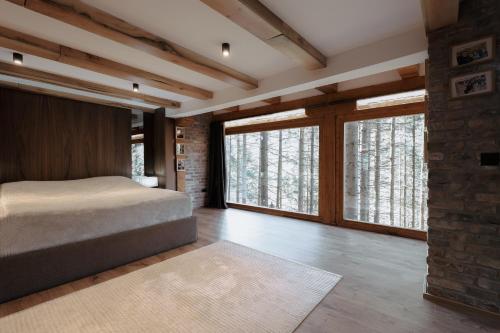 a bedroom with a bed and large windows at Seraphine Chalet in Peje