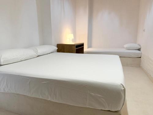 a white bedroom with two beds and a table at SĀN Living in Golem