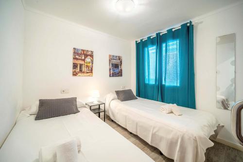 two beds in a room with blue curtains at Piso Marina by Sealand Villas in Port de Pollensa